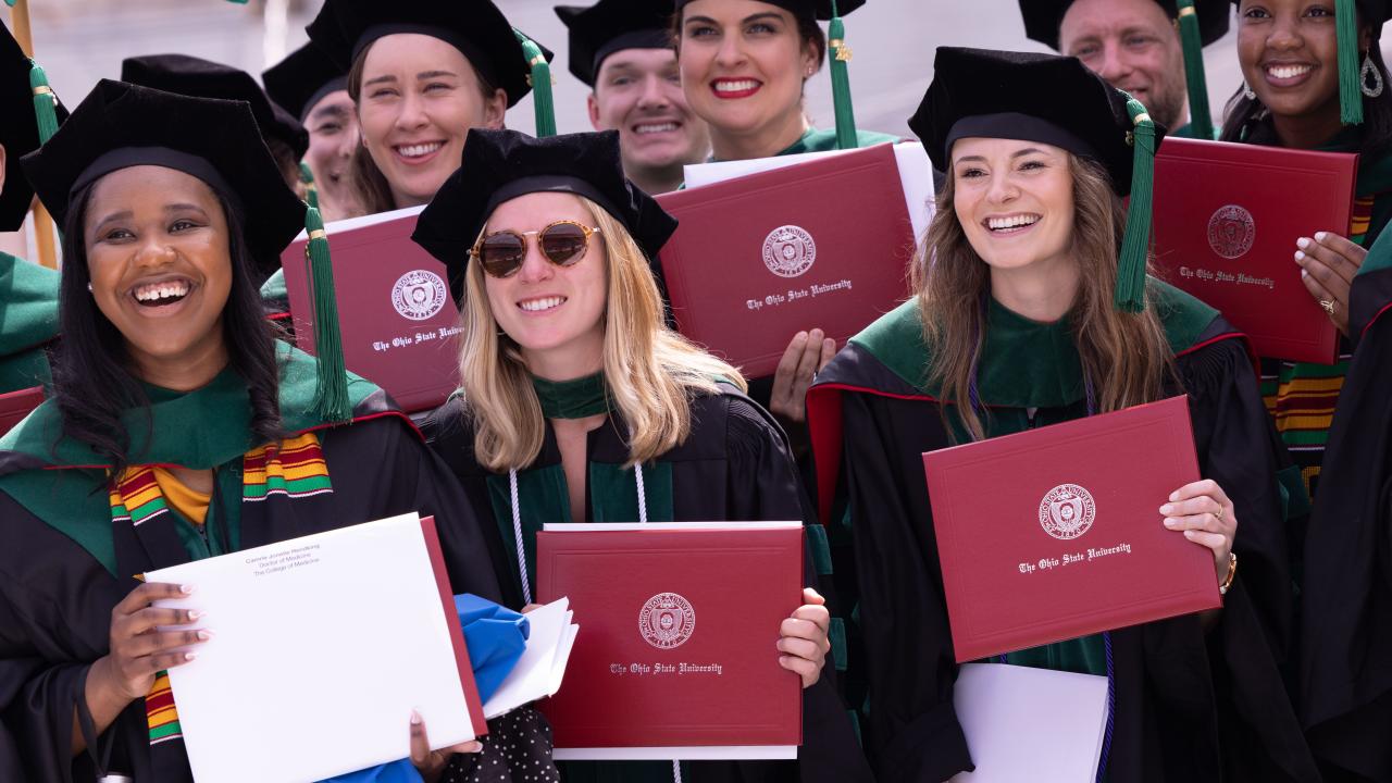 students holding their diplomas at graduation